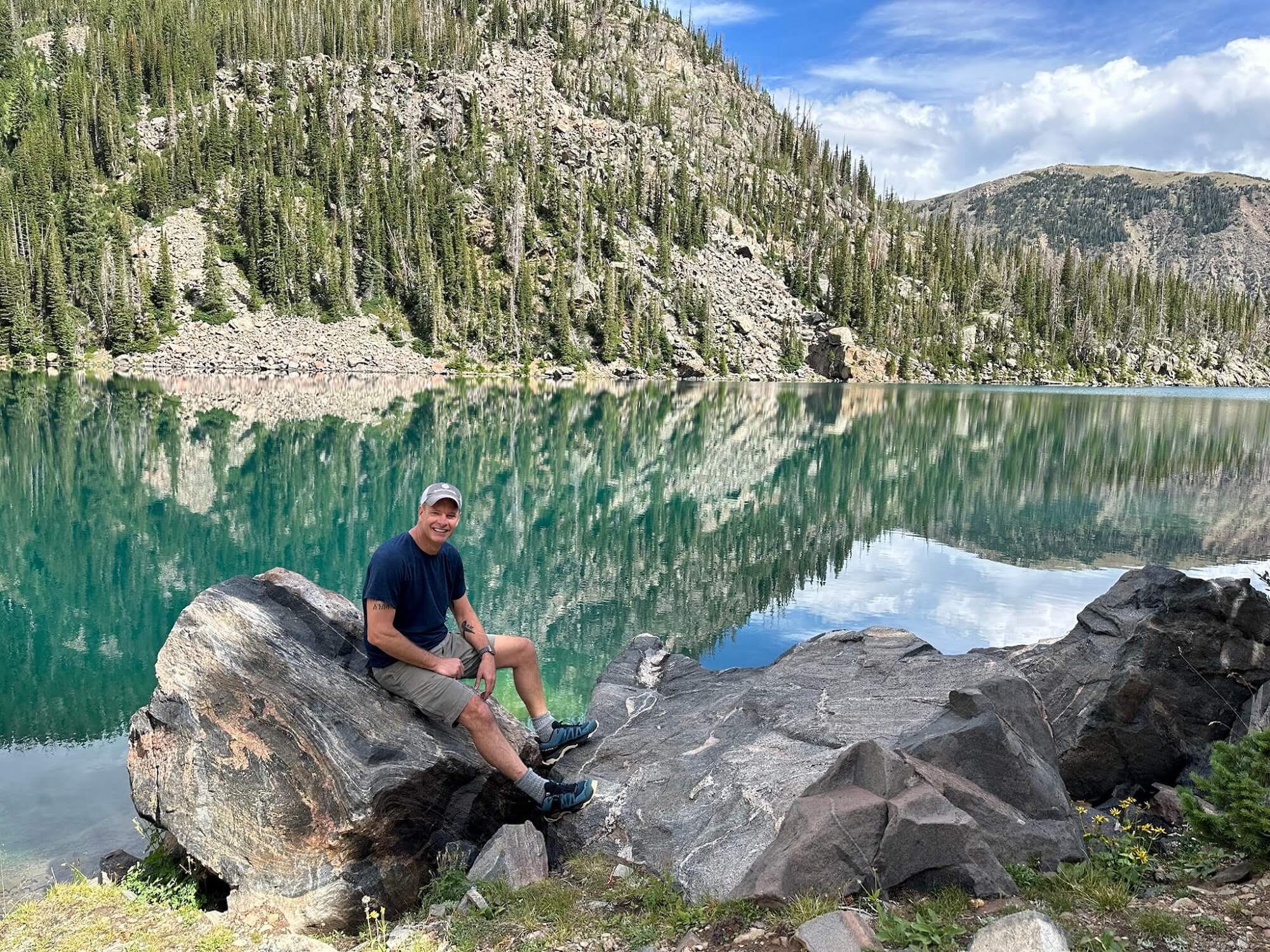 Shane Smith outside posing on a rock in front of a lake